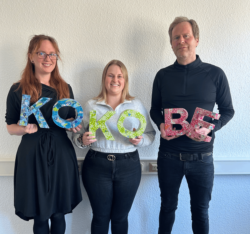 Gruppenfoto des Teams. Jeder hält eine Silbe des Namen KoKoBe in Händen.